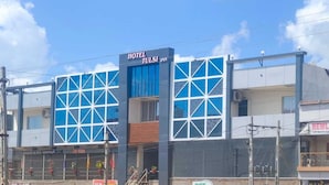 A hotel with a modern architectural design, featuring large windows and a prominent sign reading "HOTEL TULSI INN".