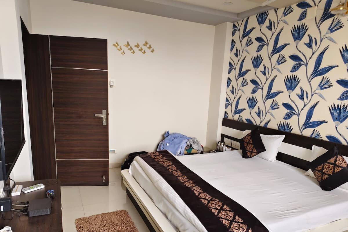 Quarto com cama, guarda-roupa de madeira, secretária com computador e parede com padrão floral.