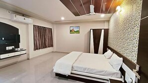 A bedroom with a bed, a wardrobe, a television, and a wall-mounted air conditioner.