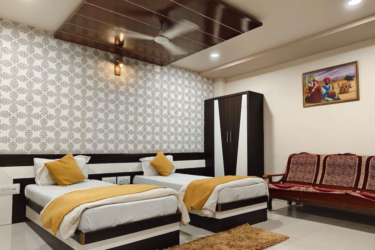 Quarto com duas camas, um guarda-roupa, um sofá e um quadro na parede.