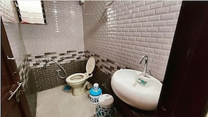A bathroom with a toilet, sink, and a shower area.