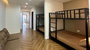Een kamer met stapelbedden, een slaapbank en een houten vloer.