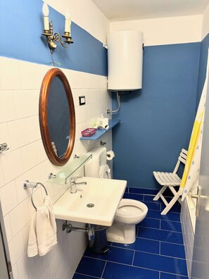 A bathroom with a white sink, mirror, toilet, and blue-tiled floor.