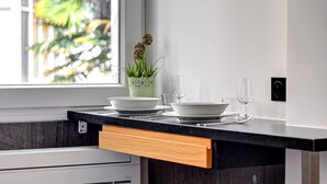 Una cocina moderna con encimera negra, armarios blancos y ventana con vistas a zonas verdes.
