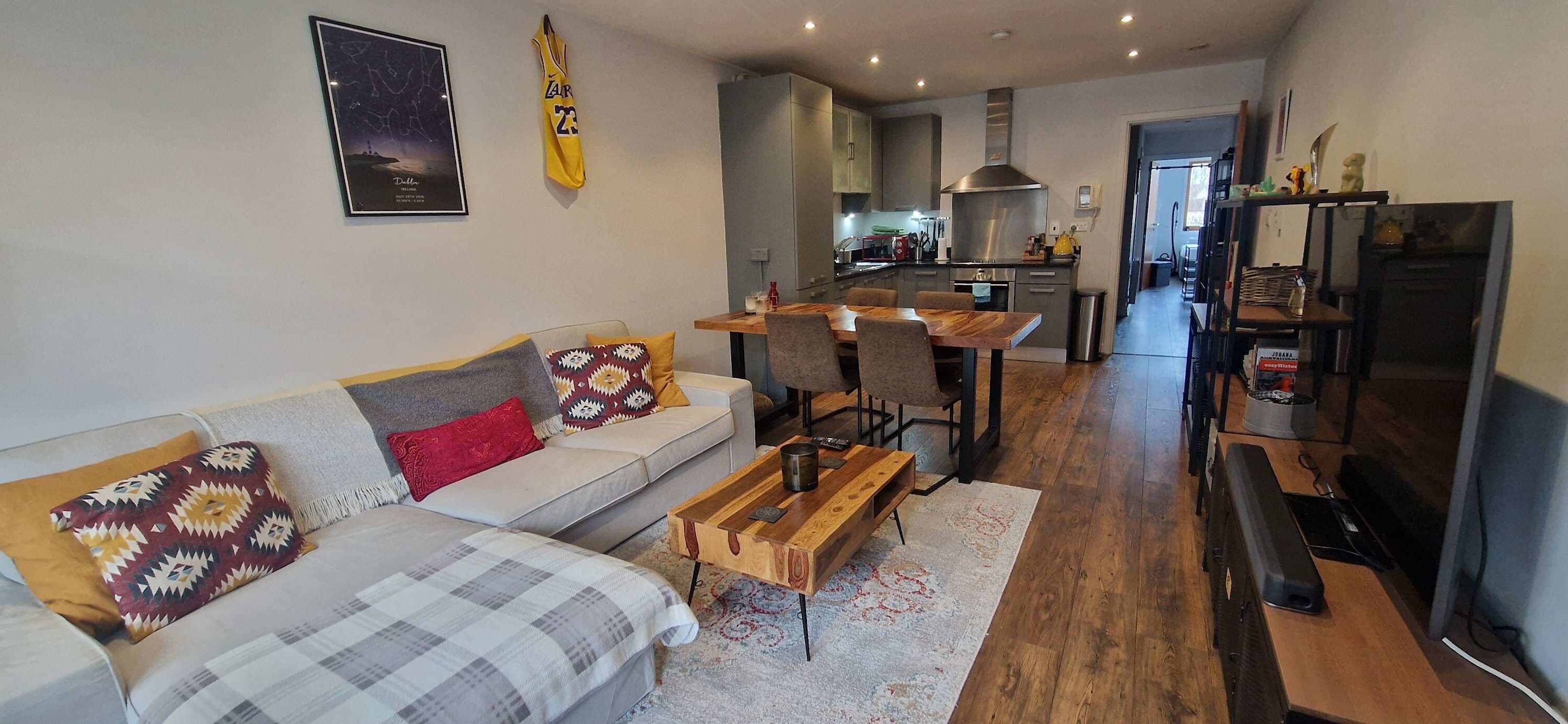 A modern living room with a sofa, coffee table, and a dining area with chairs.