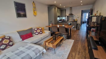 A modern living room with a sofa, coffee table, and a dining area with chairs.
