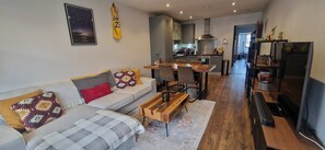A modern living room with a sofa, coffee table, and a dining area with chairs. - Cool n Comfy 2BD in Irishtown, D4 Beside Aviva (Dublin)
