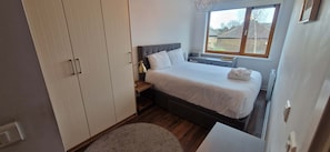 A bedroom with a bed, bedside table, lamp, window, and wardrobe. - Cool n Comfy 2BD in Irishtown, D4 Beside Aviva (Dublin)