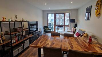 A dining area with a wooden table, chairs, a bookshelf, and a sofa.