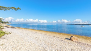 A pebbled beach with a clear blue sky and calm water. - Charming 2-bedroom cottage in Sag Harbor with AC, WiFi (Sag Harbor)