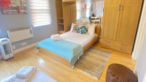 Une chambre à coucher avec un lit, une armoire en bois et un radiateur.