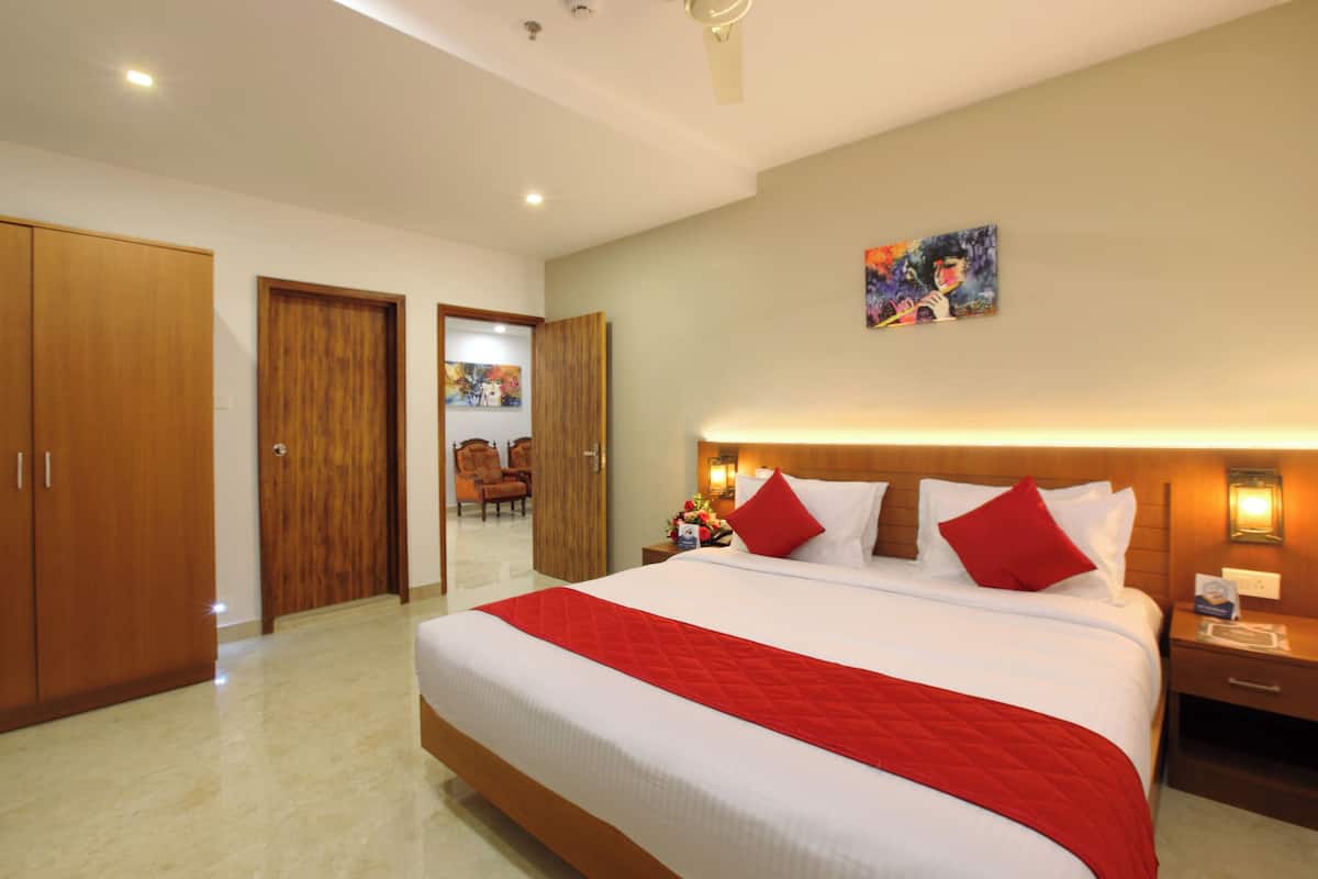 Una habitación de hotel con una cama grande, un armario de madera, un cuadro en la pared y una mesita de noche con lámpara.