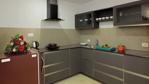 Cocina moderna con gabinetes grises, pileta de acero inoxidable y horno empotrado. Hay un arreglo floral en la encimera y un hervidor.