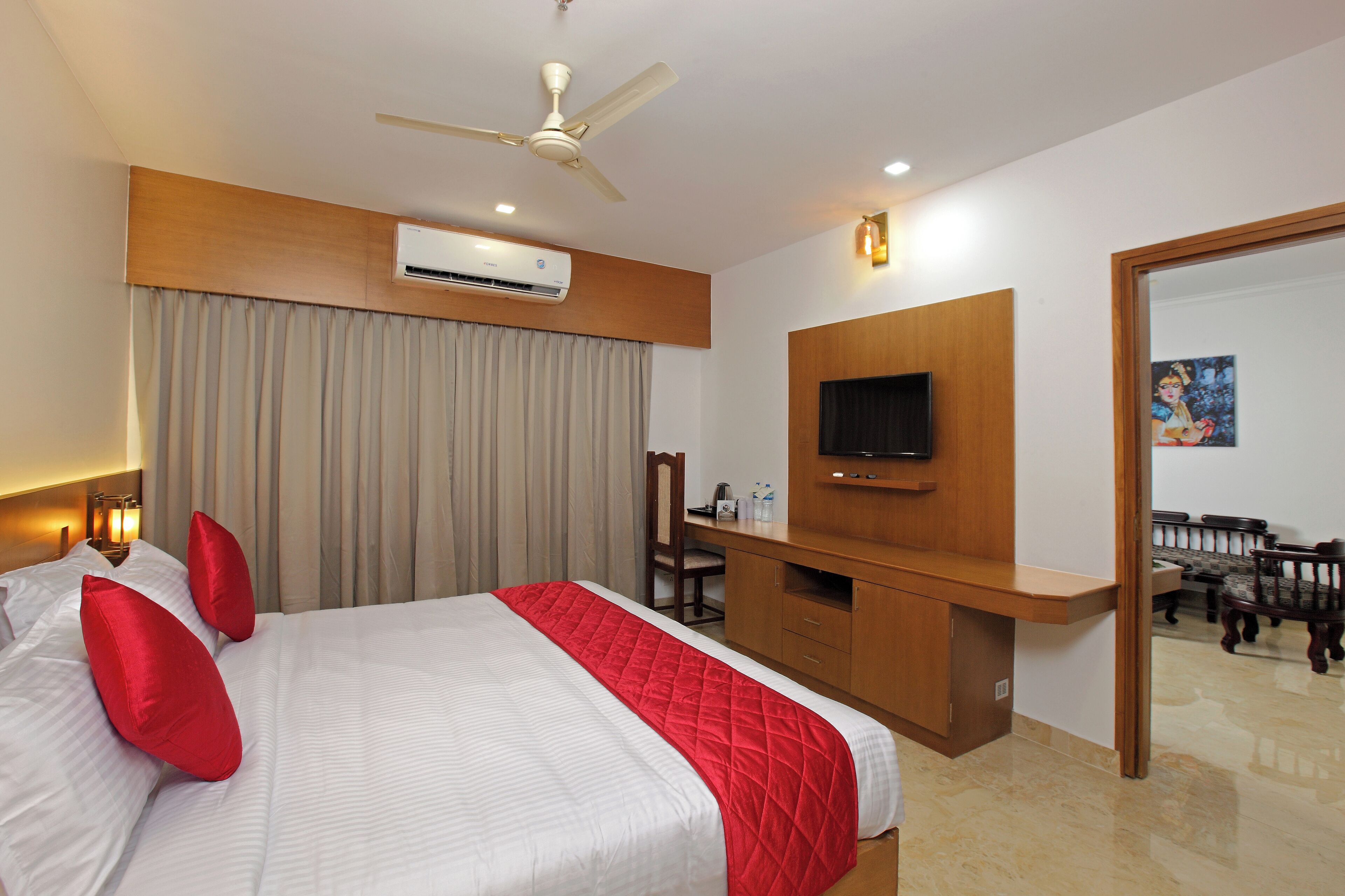 A hotel room with a bed, a desk, a TV, and a mirror.