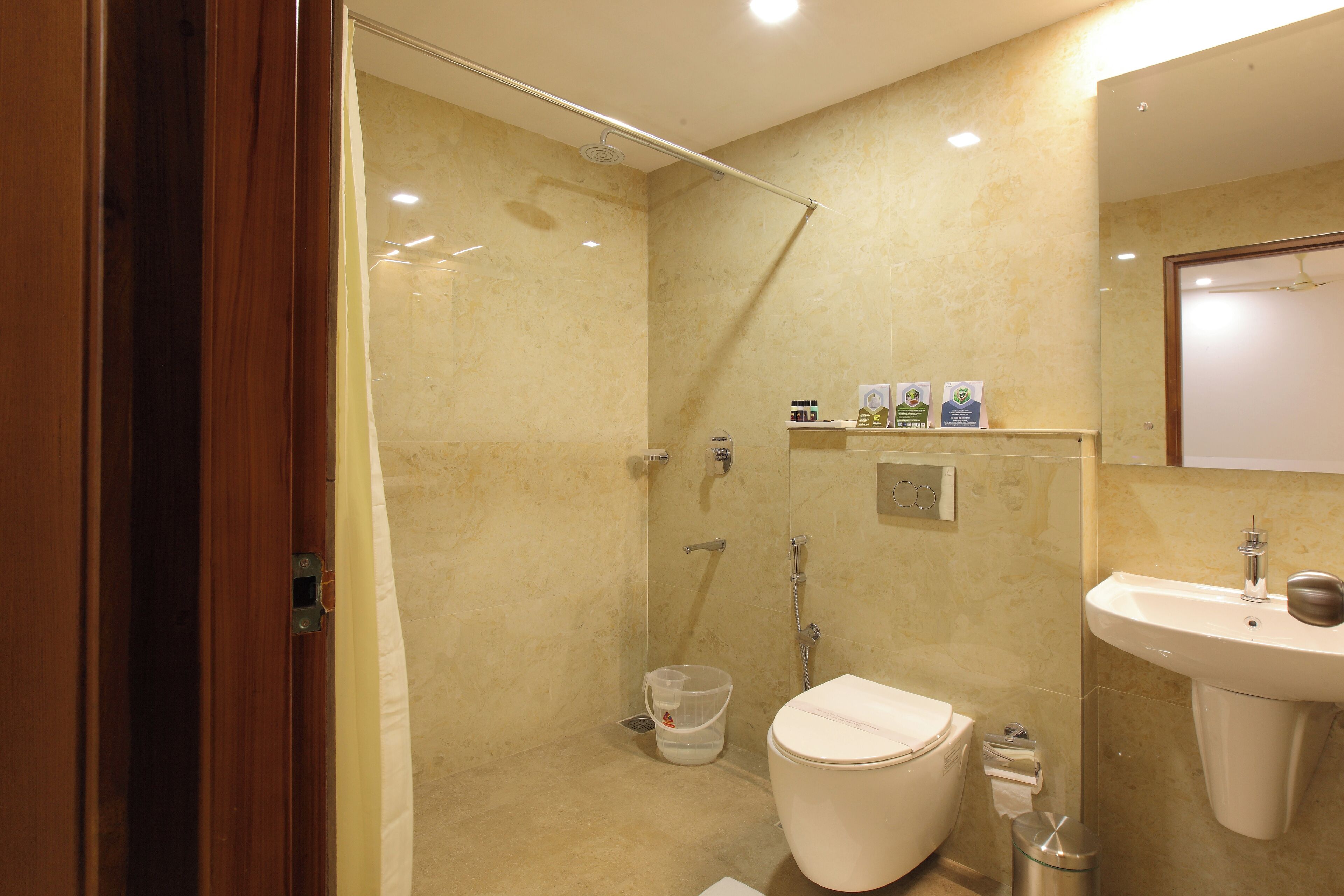 A bathroom with a shower, toilet, sink, and a mirror.