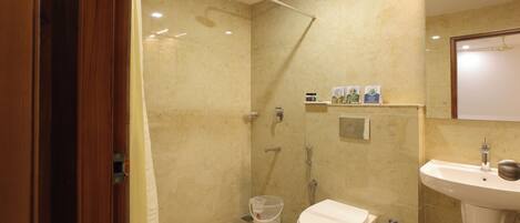 A bathroom with a shower, toilet, sink, and a mirror.