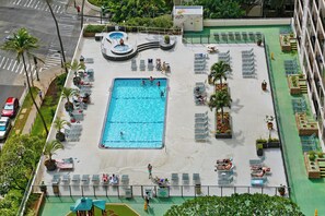 En vy från ovan av ett poolområde på ett tak, med en stor swimmingpool, solstolar och ett bubbelbad.