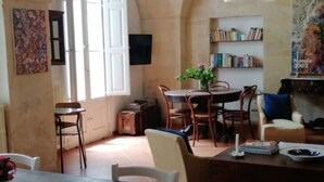 A cozy dining area with a round table, chairs, and a bookshelf filled with books. - Le Volte di San Leonardo (Lecce)