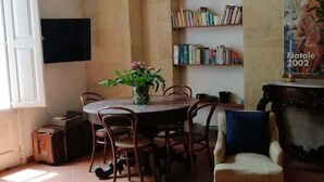 A dining area with a round table, chairs, a vase of flowers, a bookshelf, and a fireplace. - Le Volte di San Leonardo (Lecce)