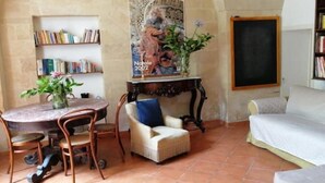 A cozy room with a round table, a chair, a bed, a bookshelf, and a poster on the wall. - Le Volte di San Leonardo (Lecce)