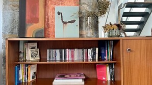Uma estante de madeira com livros e objetos decorativos em frente a uma parede de pedra.
