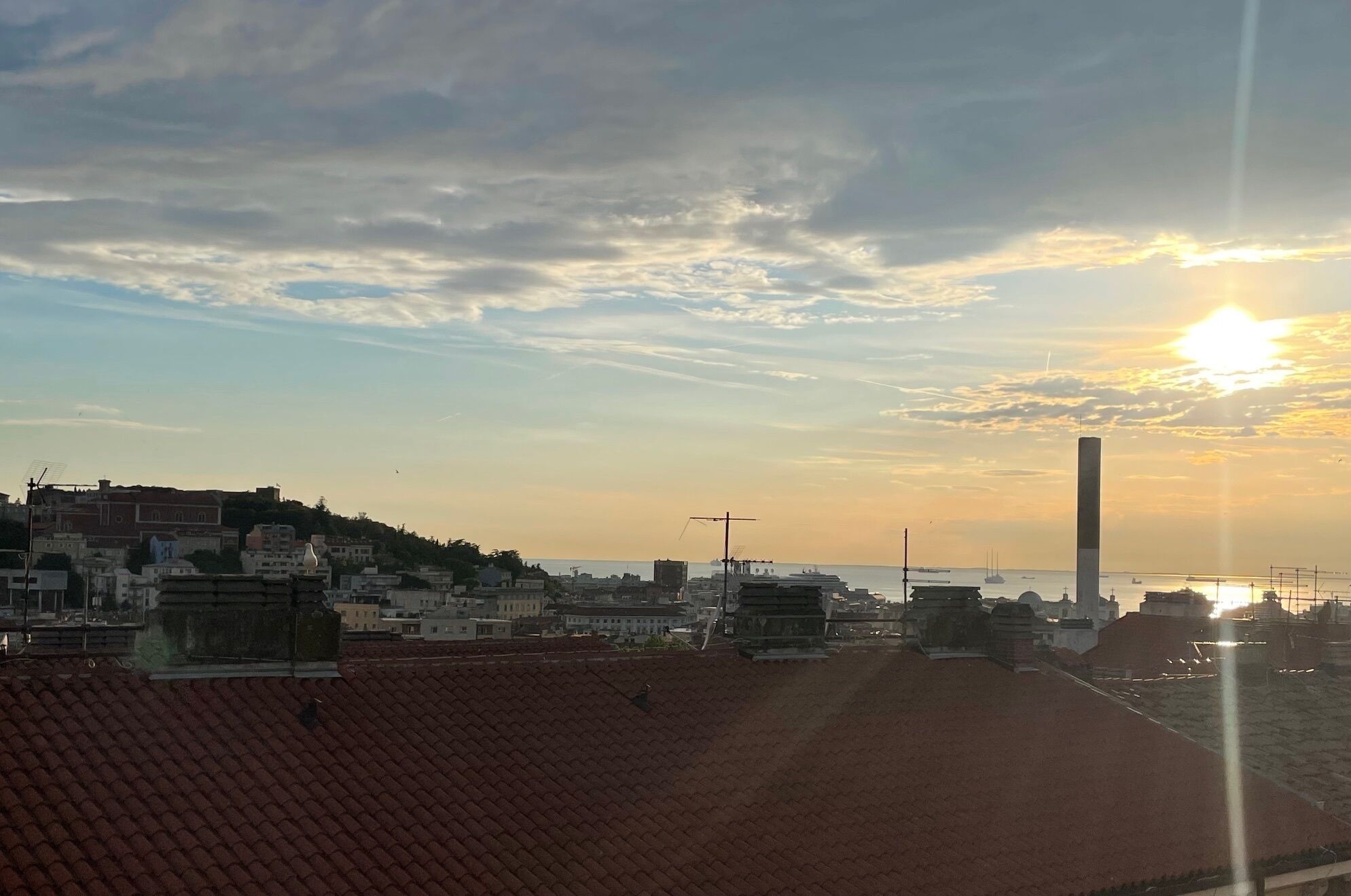Paesaggio costiero con una torre imponente e un tramonto sull'acqua.