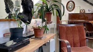Um interior moderno com uma escrivaninha de madeira, plantas em vasos, uma cadeira vermelha e uma escada.