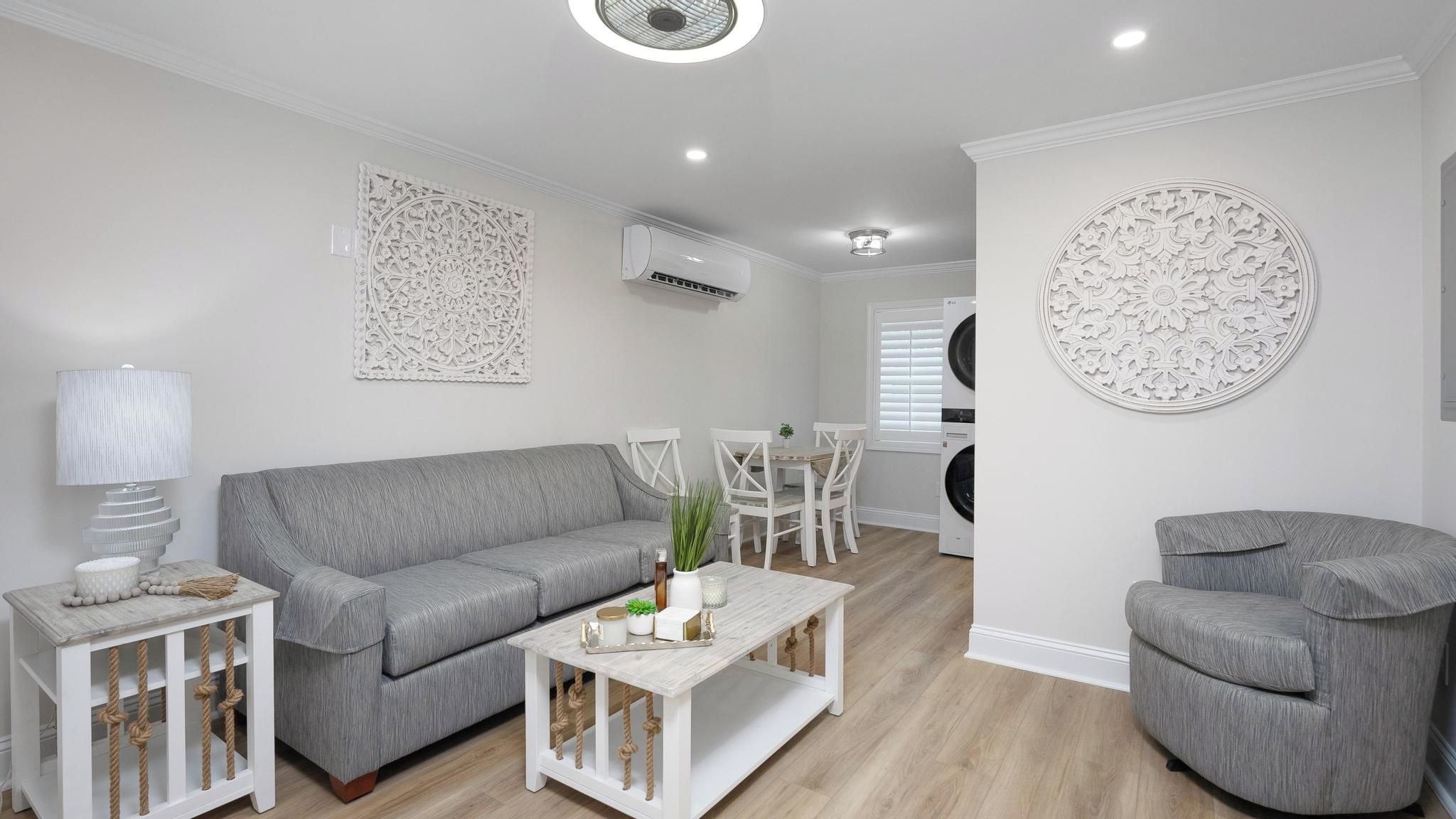 A modern living room with a grey sofa, a coffee table, and a round decorative wall piece.