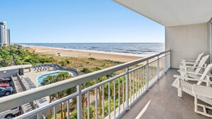 A balcony with a view of the beach and ocean, white chairs, and a pool area. - S Hampton 409 1 Br Oceanfront in Kingston, Pool (Myrtle Beach)