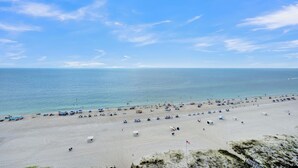 A beach with umbrellas and beachgoers. - Lighthouse 1104 by Liquid Life (Gulf Shores)