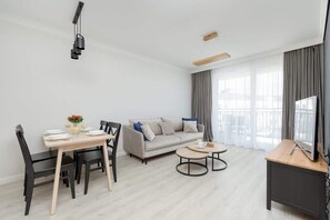 A modern living room with a dining table, sofa, and TV stand.