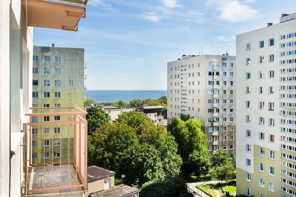 A high-rise building with multiple floors, balconies, and a view of the sea.
