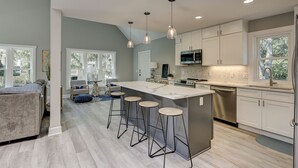 A modern kitchen with a large island, bar stools, and pendant lighting.