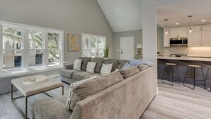 A spacious living room with a large grey sectional sofa, a small round table, and a ceiling fan.