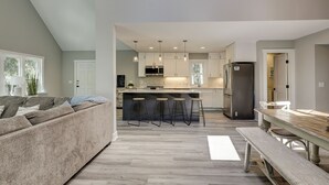 A modern kitchen with a central island, bar stools, and a refrigerator.