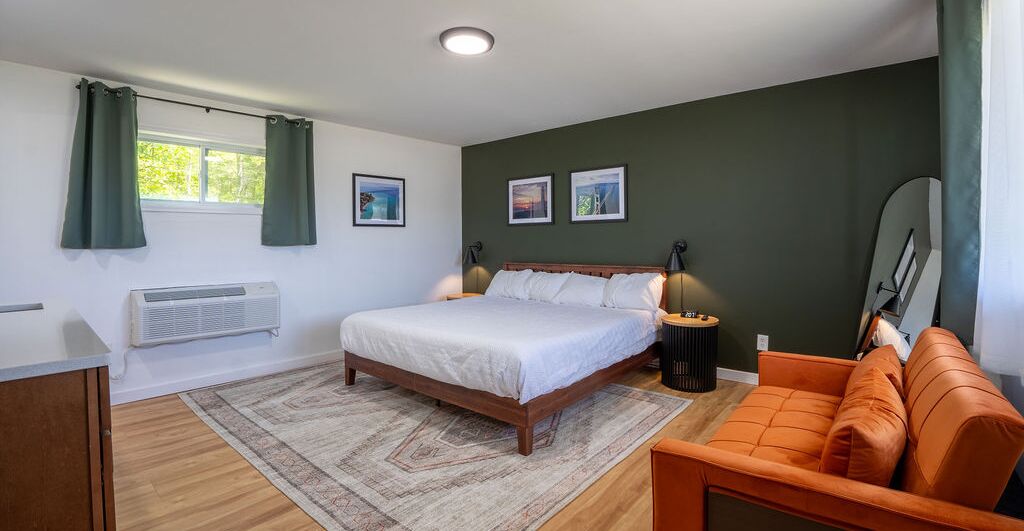 Une chambre à coucher comprenant un lit, une table de chevet, une commode, un miroir et un canapé.