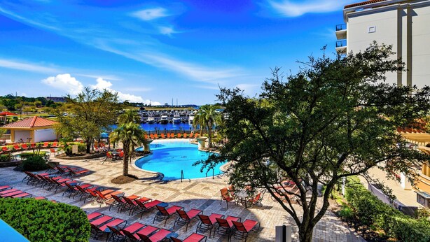 Ein Resort mit Swimmingpool, Liegestühlen und Blick auf den Hafen.