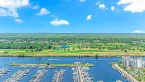 Ein Yachthafen mit vertäuten Booten, ein Golfplatz und Wohnhäuser im Hintergrund.