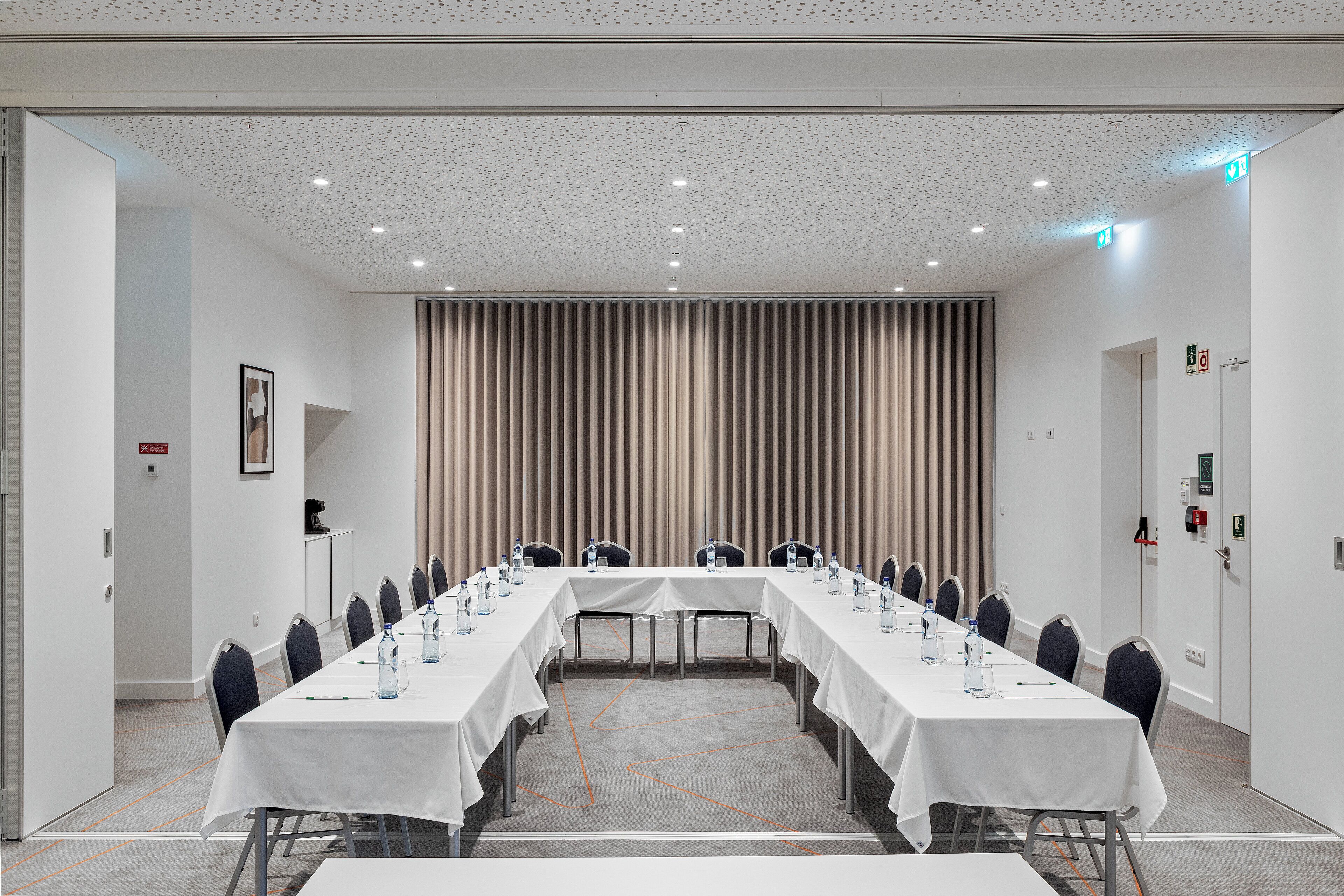 A conference room with a long table, chairs, and a curtain backdrop.