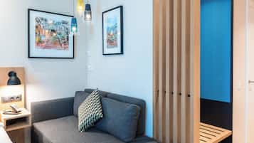 A modern room with a grey sofa, a wooden bench, and two framed artworks on the wall.