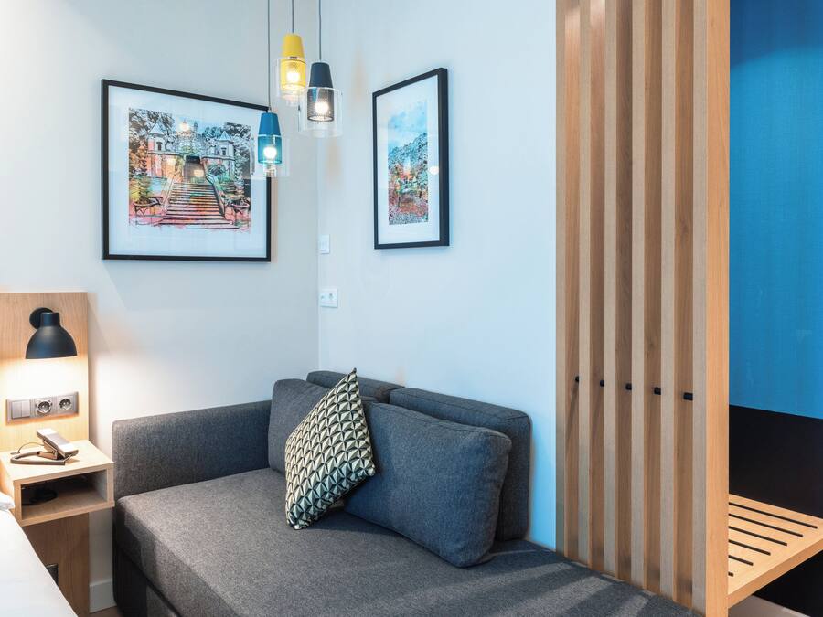 A modern room with a grey sofa, a wooden bench, and two framed artworks on the wall.