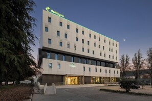 Een Holiday Inn hotel met een modern design, herkenbaar aan het platte dak en de ruime entree met glazen deuren.