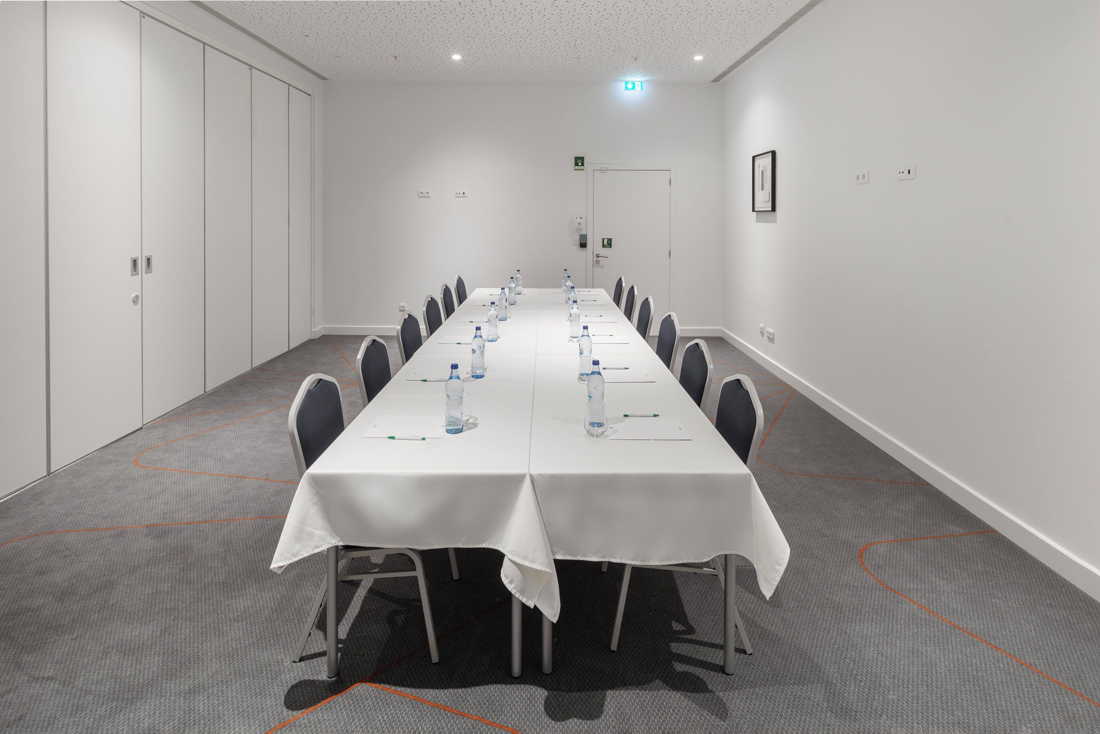 A conference room with a long table, chairs, and water bottles.