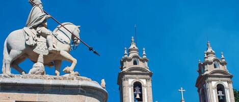 A statue of a figure on horseback in front of a church with two bell towers.