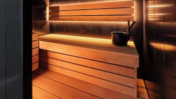 Een sauna met houten banken en een zwarte pot op de bank.