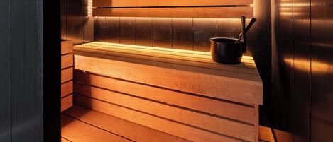 A sauna with wooden benches and a black pot on the bench.