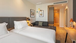 A hotel room with a large bed, a sofa, a desk, and a mirror. - Holiday Inn Braga by IHG (Braga)