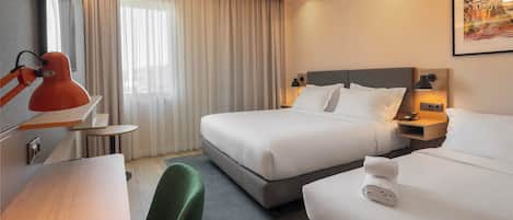 A hotel room with two beds, a desk, a chair, a TV, and a window with curtains.