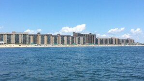 A beachfront hotel with multiple floors, a sandy beach, and a clear blue sky.