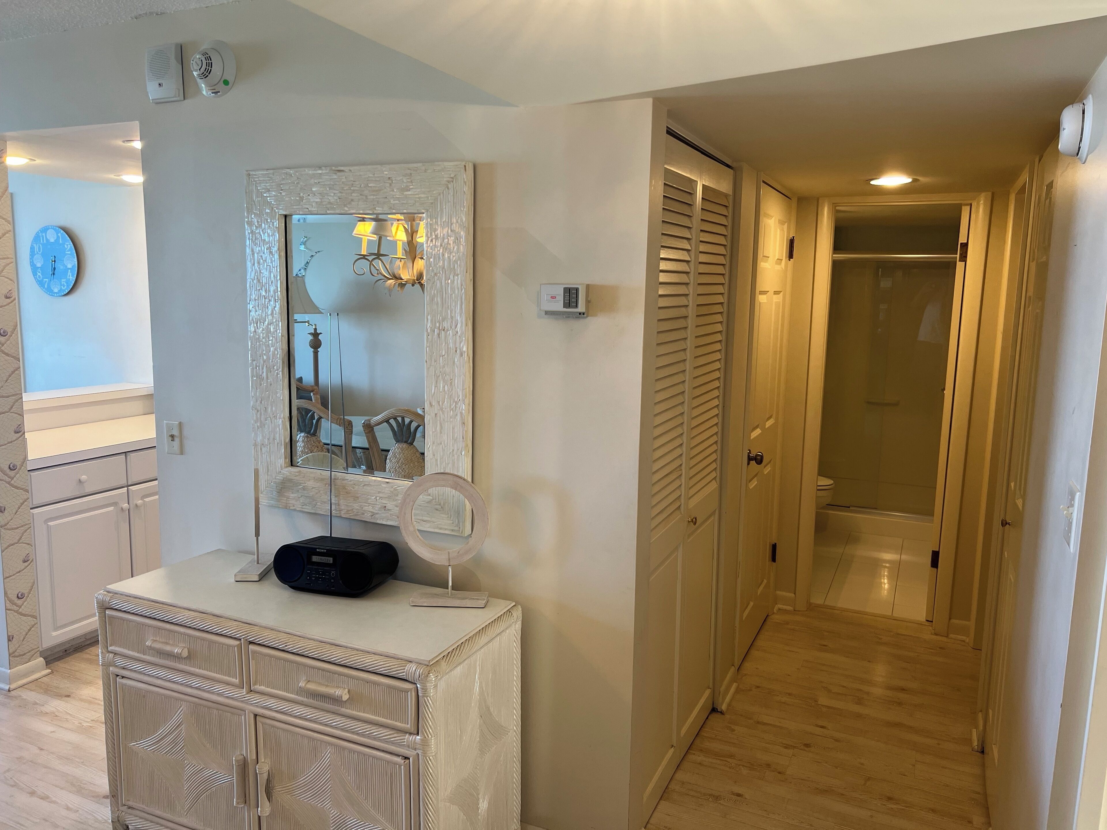 Une chambre d’hôtel équipée d’une coiffeuse, d’un miroir, d’une radio et d’un dressing.